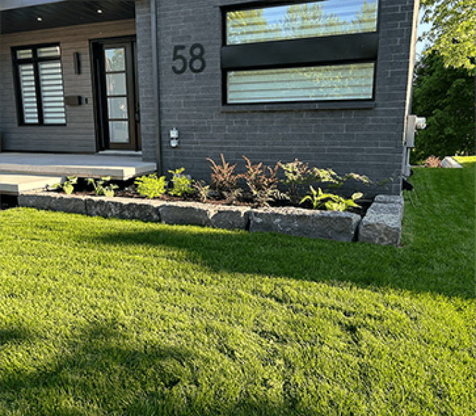 Plate-bande moderne avec muret de pierre et gazon – Aménagement Marosa à Lévis